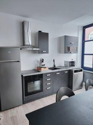 een keuken met roestvrijstalen apparatuur en een tafel bij At Dream appartement in Bergues