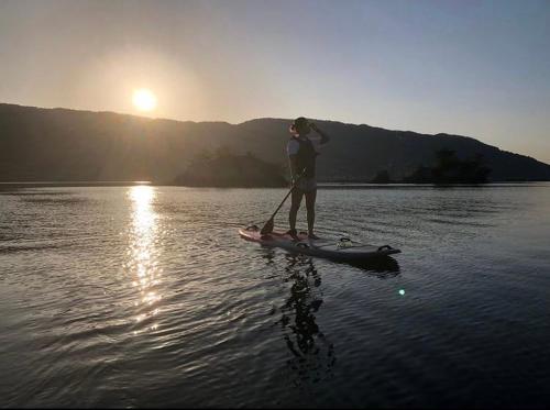 a man standing on a paddle board in the water at 体験民宿NORA in Mukaigawa