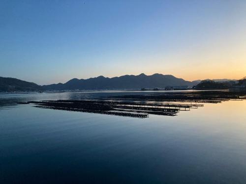 a large body of water with mountains in the background at 体験民宿NORA in Mukaigawa