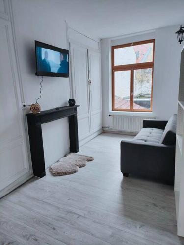 een woonkamer met een bank en een tv aan de muur bij At Dream appartement in Bergues