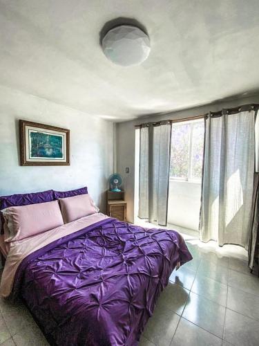 a bedroom with a purple bed and a window at Departamento a 25 min del AIFA in Ecatepec