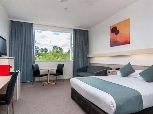 a hotel room with a bed and a desk and a window at Comfort Inn Regal Park in Adelaide