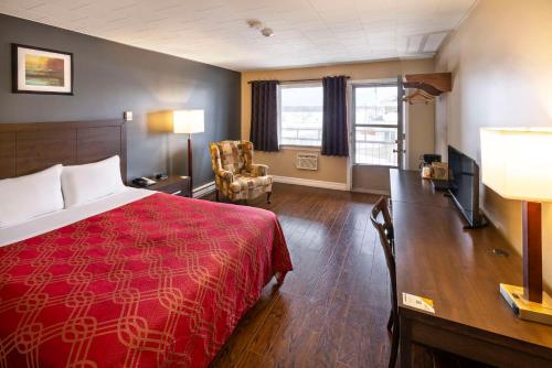 a hotel room with a red bed and a living room at Econo Lodge Miramichi in Miramichi