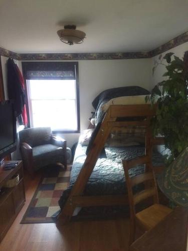 1 dormitorio con litera y silla en Rustic Quaint Cabin In the woods--Pets welcomed, en Dunnsville