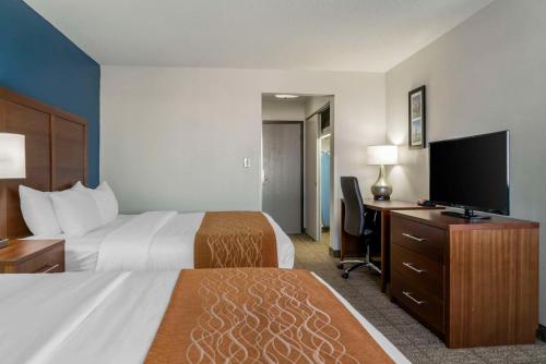 a hotel room with two beds and a desk with a television at Comfort Inn East Oregon - Toledo in Oregon