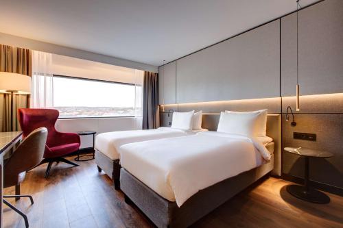 a hotel room with a large bed and a red chair at Radisson Blu Scandinavia Hotel, Oslo in Oslo