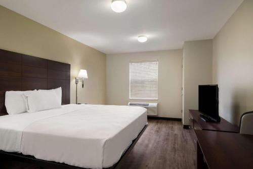 a bedroom with a large white bed and a television at Suburban Studios Denver Central-Arvada in Arvada