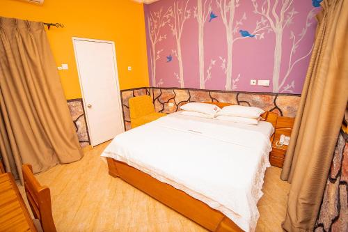 - une chambre dotée d'un lit avec des draps blancs et des oiseaux sur le mur dans l'établissement Hilton View Hotel, à Accra
