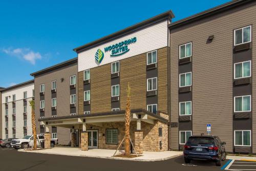 a hotel building with a car parked in a parking lot at WoodSpring Suites Jacksonville Orange Park in Orange Park