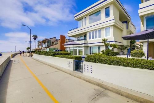 a white house on a sidewalk next to the beach at 125-fun In The Sun Penthouse in San Diego
