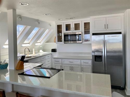 a kitchen with white cabinets and a stainless steel refrigerator at 125-fun In The Sun Penthouse in San Diego