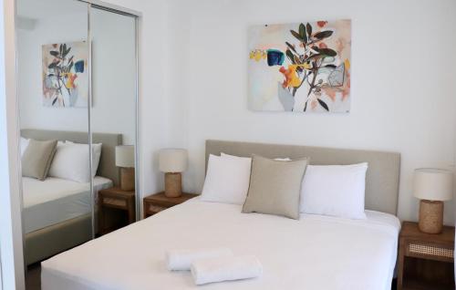 a bedroom with a white bed and a mirror at X Kirra Apartments in Gold Coast