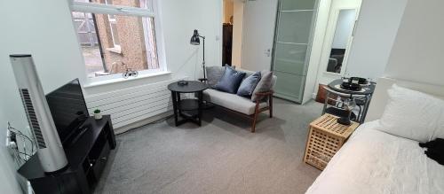 a bedroom with a bed and a chair and a television at Cosy flat - with excellent transport links in South Norwood