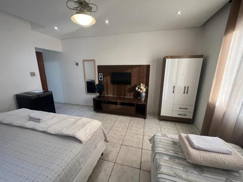 um quarto com uma cama, uma televisão e um sofá em Travessa 12 - Suítes centro de Serra Negra - SP em Serra Negra