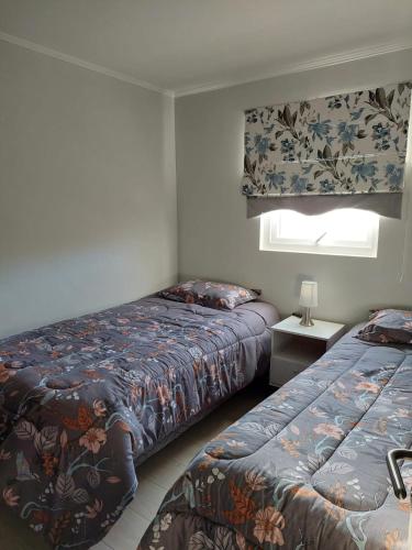a bedroom with two beds and a window at Hermoso departamento nuevo en Pucon equipado con 3 dormitorios wifi y estacionamiento privado a 5 minutos del centro y lago in Pucón