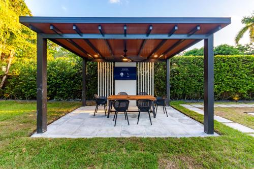 a wooden pavilion with a table and chairs in the grass at Fascinating Luxe Two-Level Villa BY THE GLAMHOMES in Biscayne Park