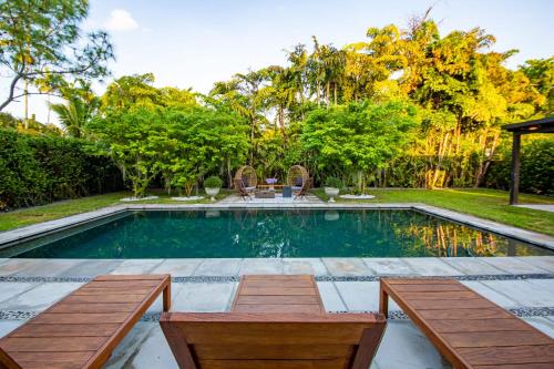 a swimming pool with two benches in a backyard at Fascinating Luxe Two-Level Villa BY THE GLAMHOMES in Biscayne Park