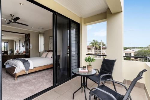 Un dormitorio con una cama y una mesa en el balcón. en Villa Sangiovese en Evans Head