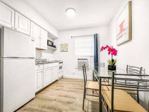 a kitchen with white cabinets and a table and a refrigerator at The Seagull in Hollywood