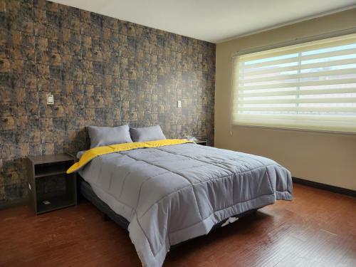 um quarto com uma cama e uma parede de tijolos em Departamento amplio 2 dormitorios em Cuenca