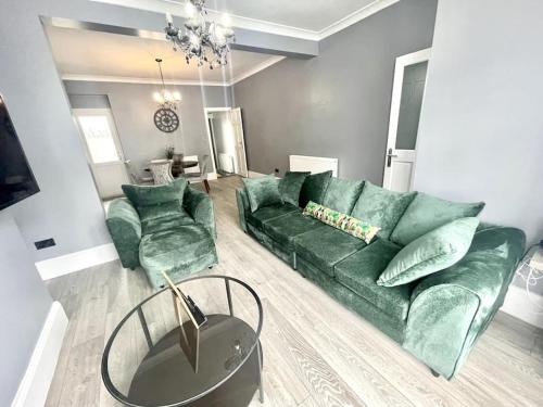 a living room with a green couch and two chairs at Spacious Modern Victorian House in Rochester in Wainscot