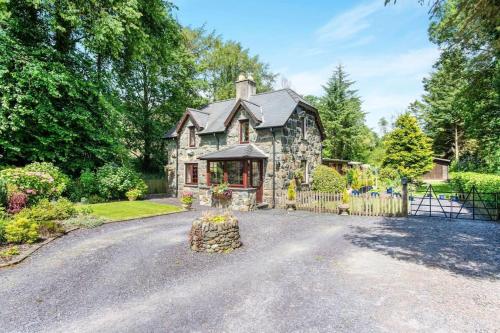 Chwilog的住宿－The Crossing Cottage - 3 bed property with games room on the Llŷn Peninsula close to Snowdonia National Park，车道前有围栏的石头房子