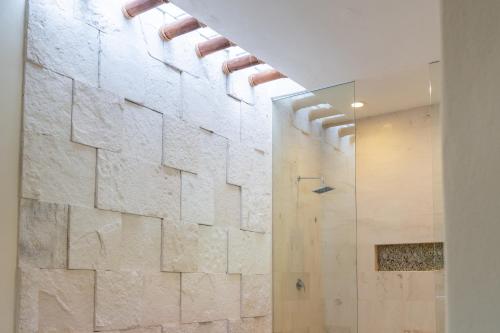 a bathroom with a shower with a stone wall at Vallarta Gardens V4 -Alberca y Roof Garden Private in Cruz de Huanacaxtle