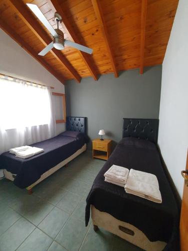 1 dormitorio con 2 camas y ventilador de techo en Cabañas Andaluhe en Villa Carlos Paz