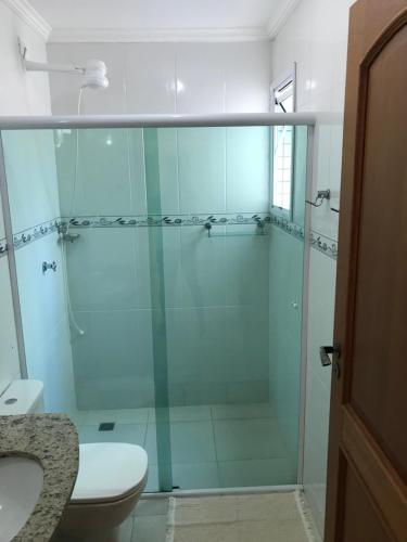 a bathroom with a glass shower with a toilet and a sink at Apartamento Ubatuba Toninhas in Ubatuba