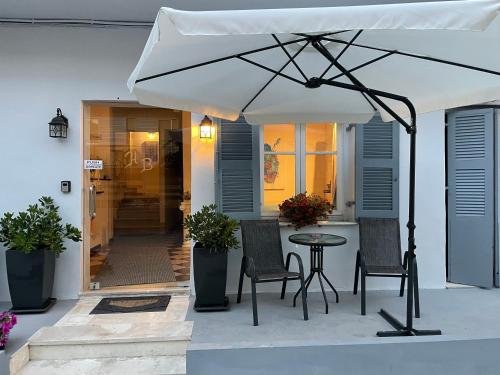 a patio with a table and chairs and an umbrella at HB Hotel Benitsa in Benitses