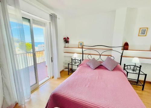 1 Schlafzimmer mit einem Bett mit einer rosa Bettdecke und einem Balkon in der Unterkunft Apartamento Maria Fernanda, in the Centre of Luz in Luz