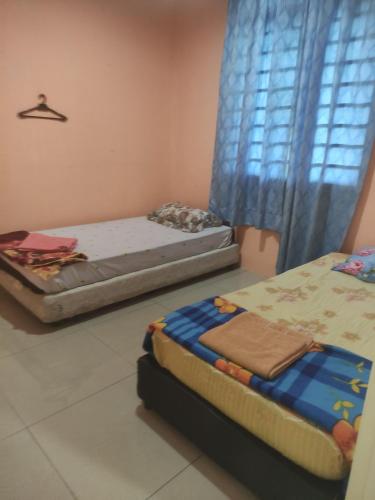 Duas camas num quarto com uma janela em Bayu Homestay em Kampong Gong Surau
