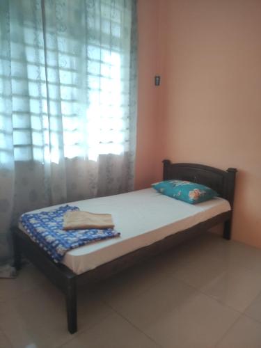 uma pequena cama num quarto com uma janela em Bayu Homestay em Kampong Gong Surau