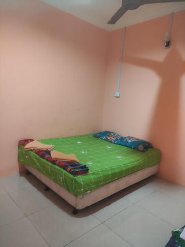 um pequeno quarto com uma cama verde num quarto em Bayu Homestay em Kampong Gong Surau