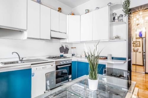 uma cozinha com armários azuis e brancos e uma mesa de vidro em Morgantini House San Siro-Duomo "Netflix & Terrace" em Milão