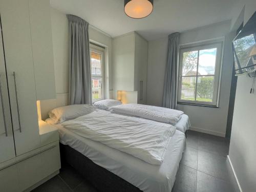 1 dormitorio con 2 camas y ventana en Beautiful wellness villa with sauna, on a holiday park on the Tjeukemeer, en Delfstrahuizen