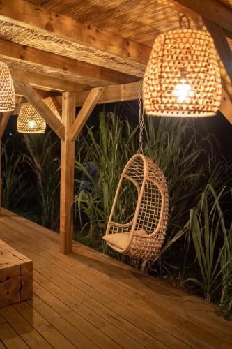 a rattan bird cage hanging from a wooden pergola at Ecolodge Anacardier - cabanon luxe pleine nature in Saint-François