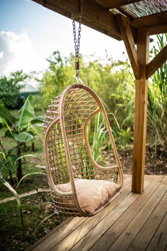 a wicker chair hanging from a porch at Ecolodge Anacardier - cabanon luxe pleine nature in Saint-François