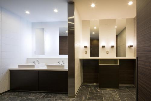 a bathroom with two sinks and two mirrors at Hotel Sunroute Chiba in Chiba