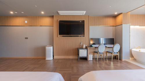 a bedroom with a bed and a desk and a tub at Yeongdo Grandbern Hotel in Busan