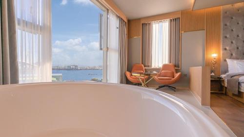 a bathroom with a tub and a bedroom with a view at Yeongdo Grandbern Hotel in Busan