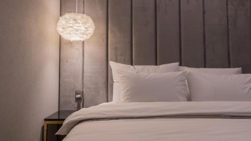 a bedroom with a large white bed with a chandelier at Yeongdo Grandbern Hotel in Busan