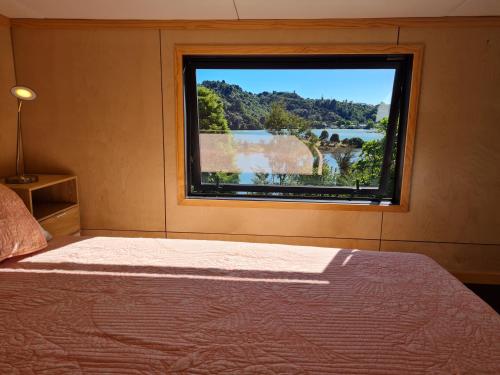 a bedroom with a window with a view of a river at Kaiteriteri Tiny Home in Kaiteriteri