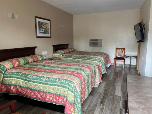 a hotel room with two beds and a table at Sunshine Inn of Daytona Beach in Daytona Beach