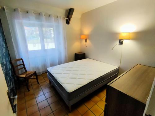 een slaapkamer met een bed, een stoel en een raam bij La Grange de Lili in Figeac