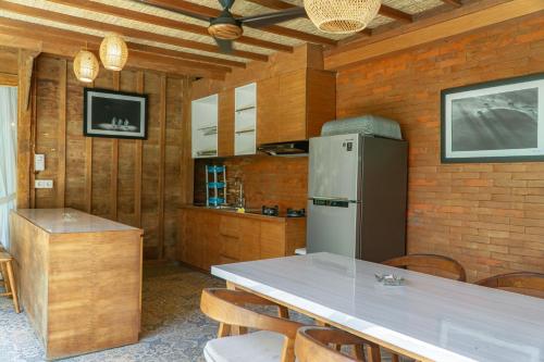 a kitchen with a table with chairs and a refrigerator at Umadhatu Resort by Amerta in Tabanan