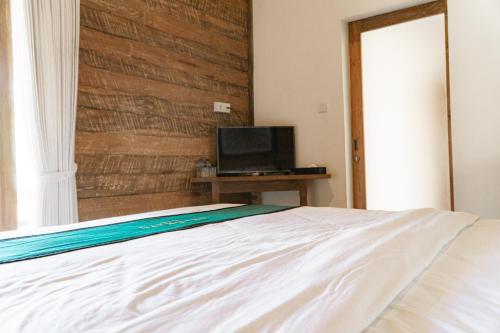 a bedroom with a white bed and a television at Umadhatu Resort by Amerta in Tabanan
