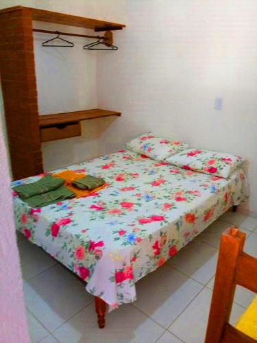 a small bed in a room with flowers on it at Pousada da Adélia in Itaúnas