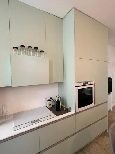 une cuisine avec des armoires blanches et un micro-ondes dans l'établissement La Belle de l’Isle, à LʼIsle-sur-la-Sorgue