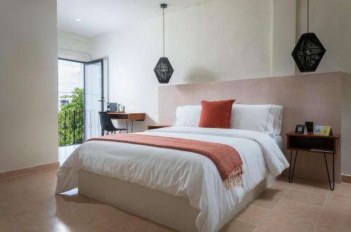 a bedroom with a bed and a desk and a window at Rodina - Hotel Boutique in Playa del Carmen